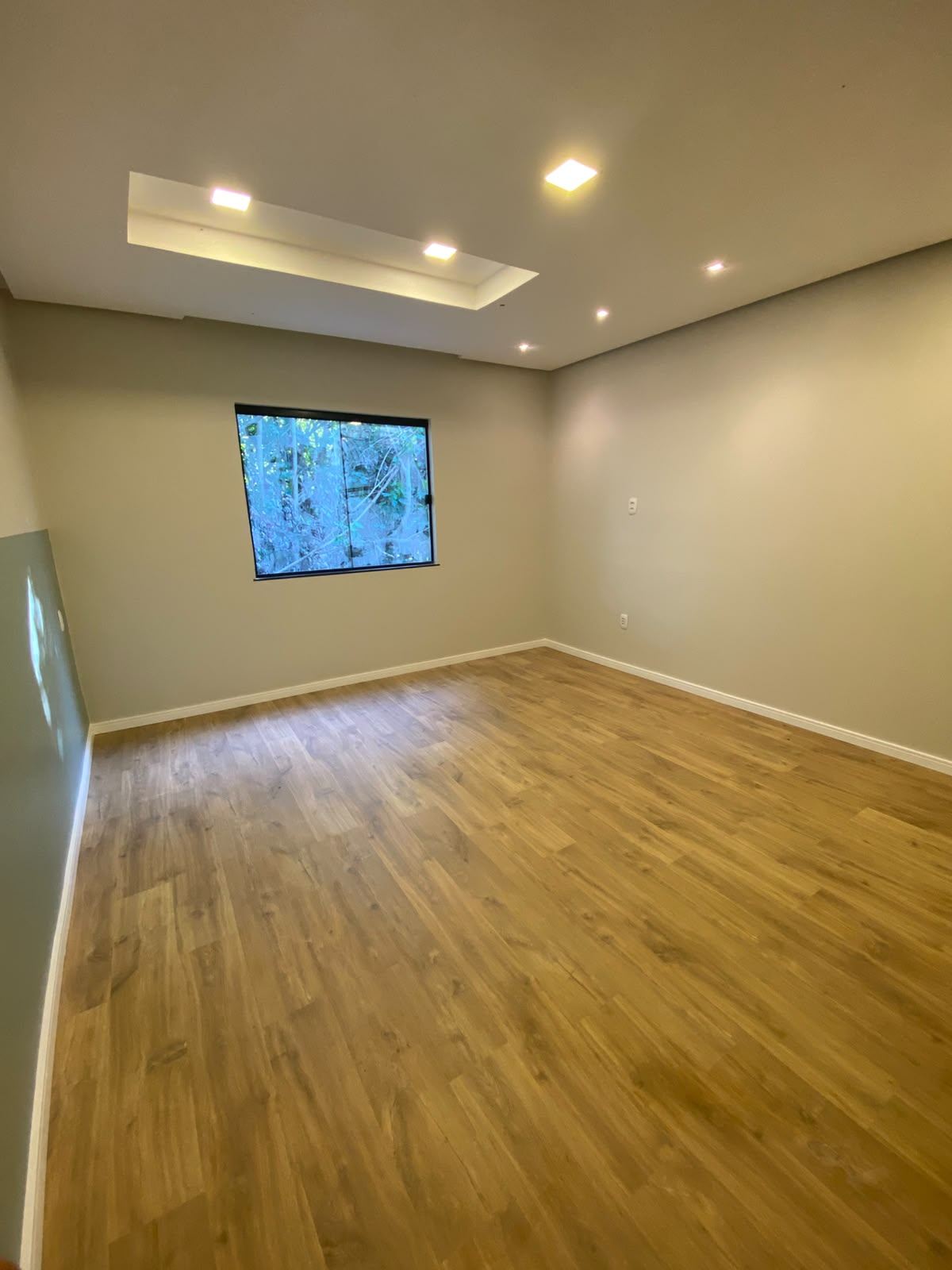 Sala ampla e iluminada com piso laminado claro