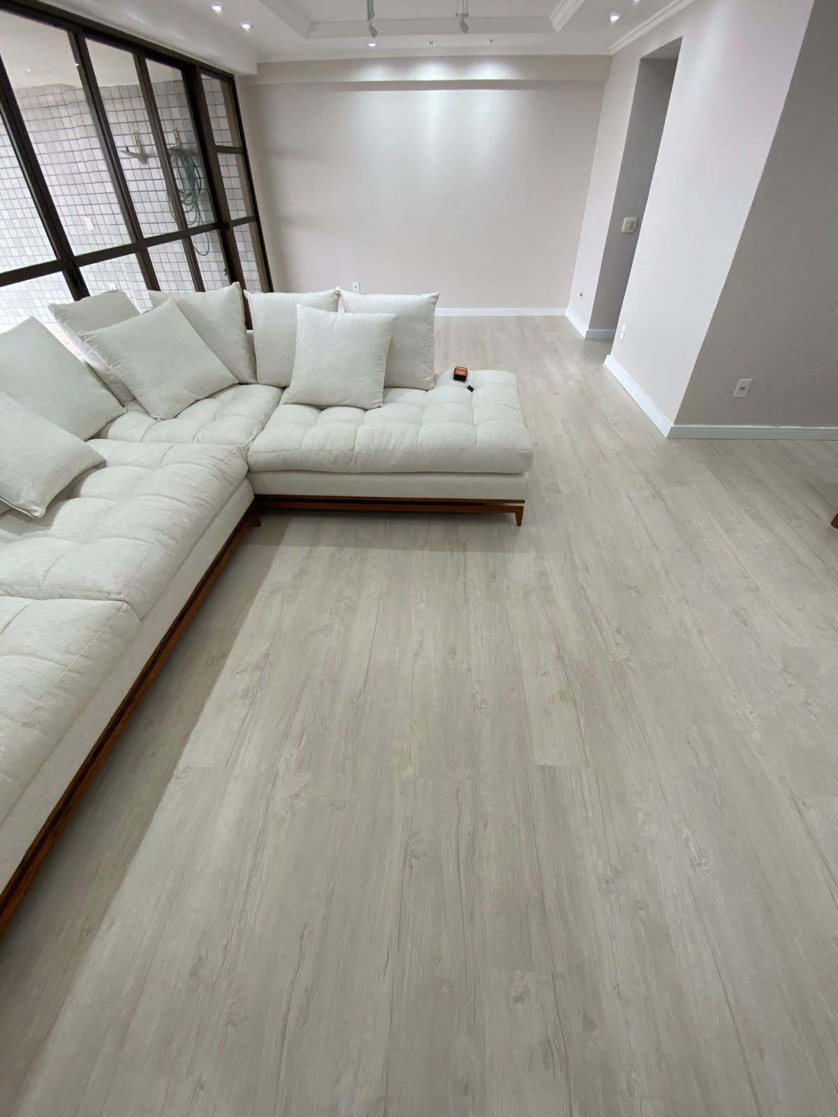 Sala de estar com piso laminado e sofá branco