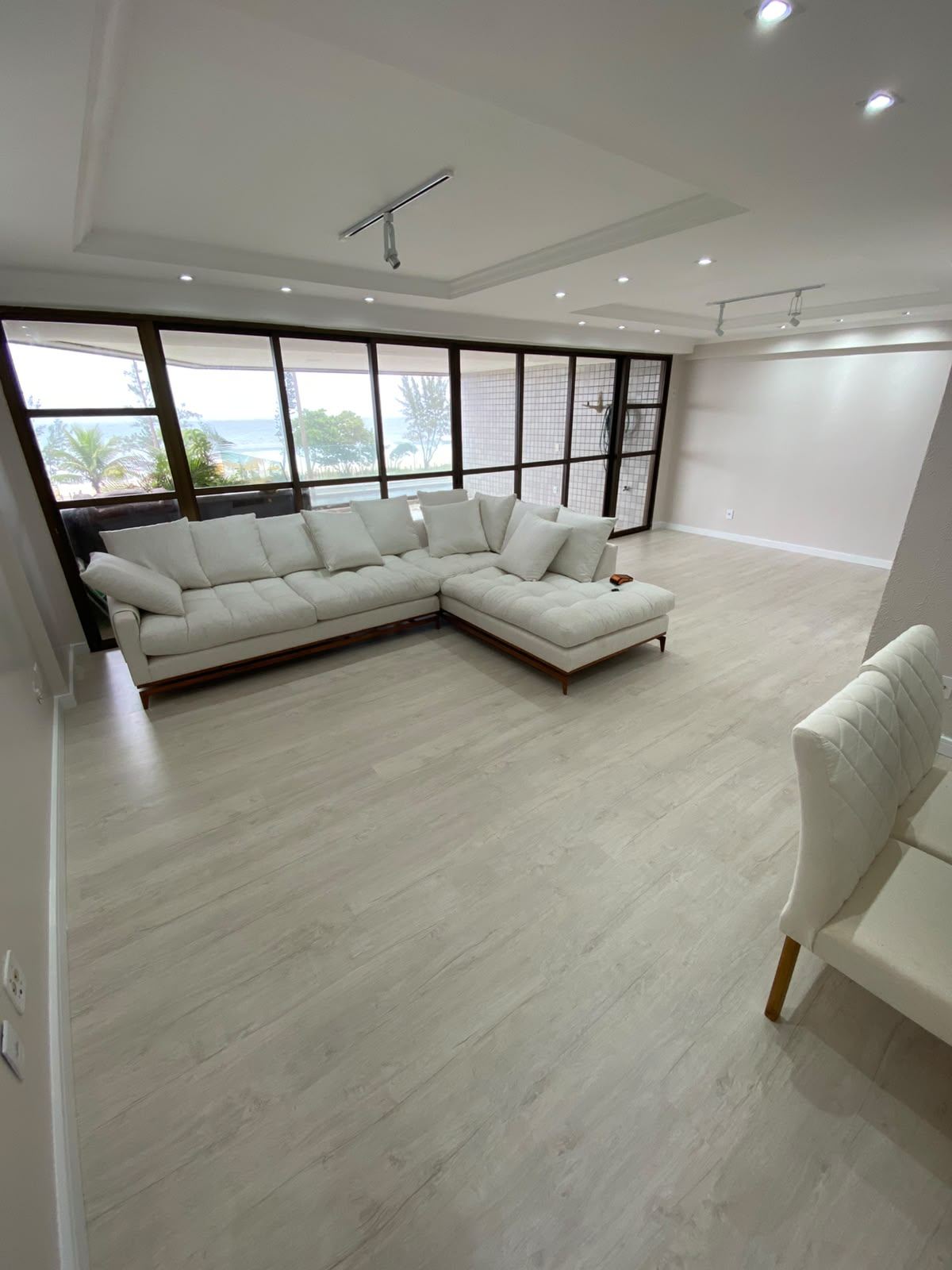 Sala com vista para o mar e piso laminado instalado pela Sobre Pisos