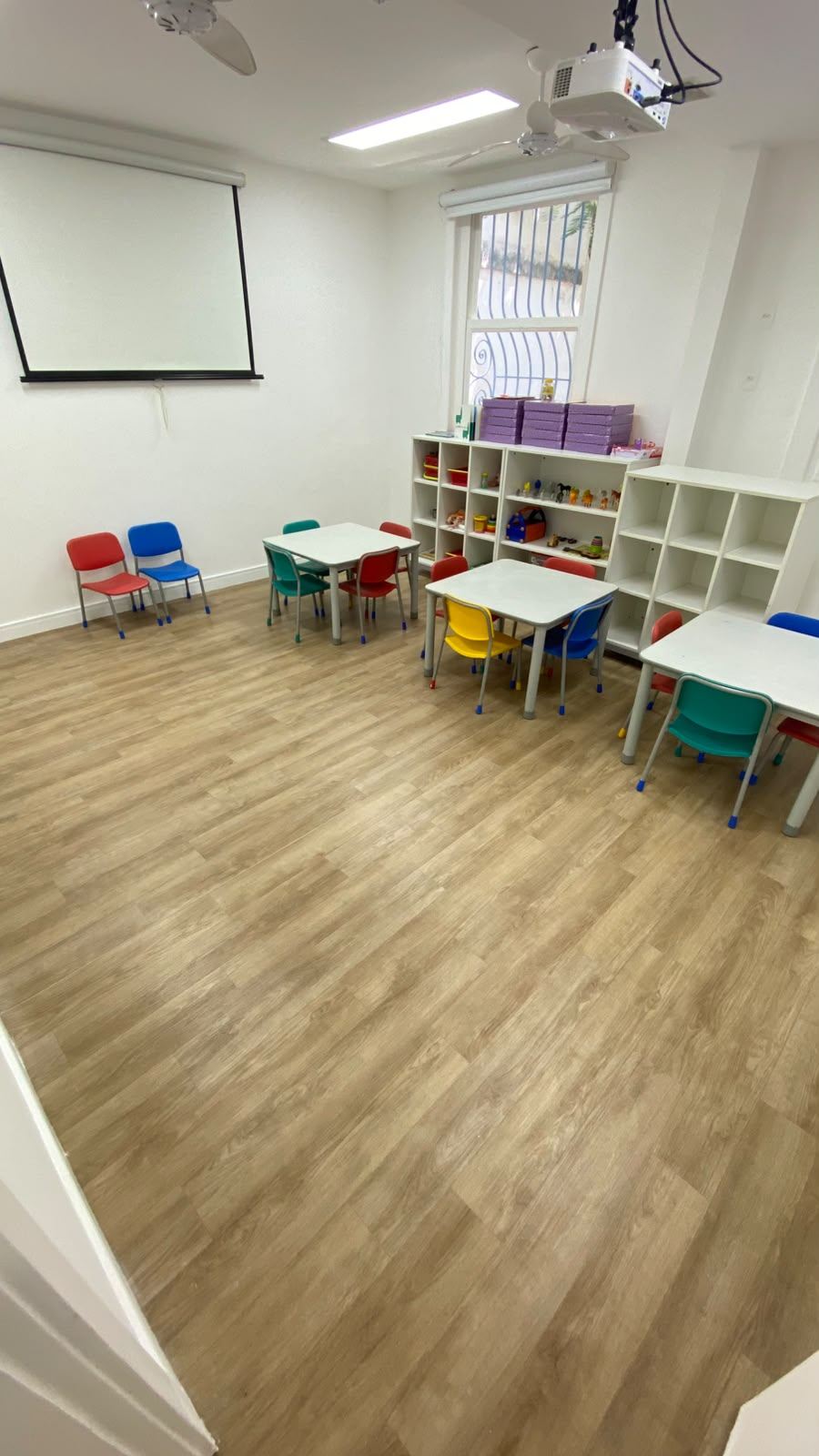 Sala comercial com piso vinílico, mesas e cadeiras infantis